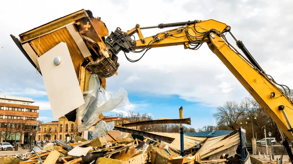 Close-up view of an excavator bucket in action during demolition at a construction site.