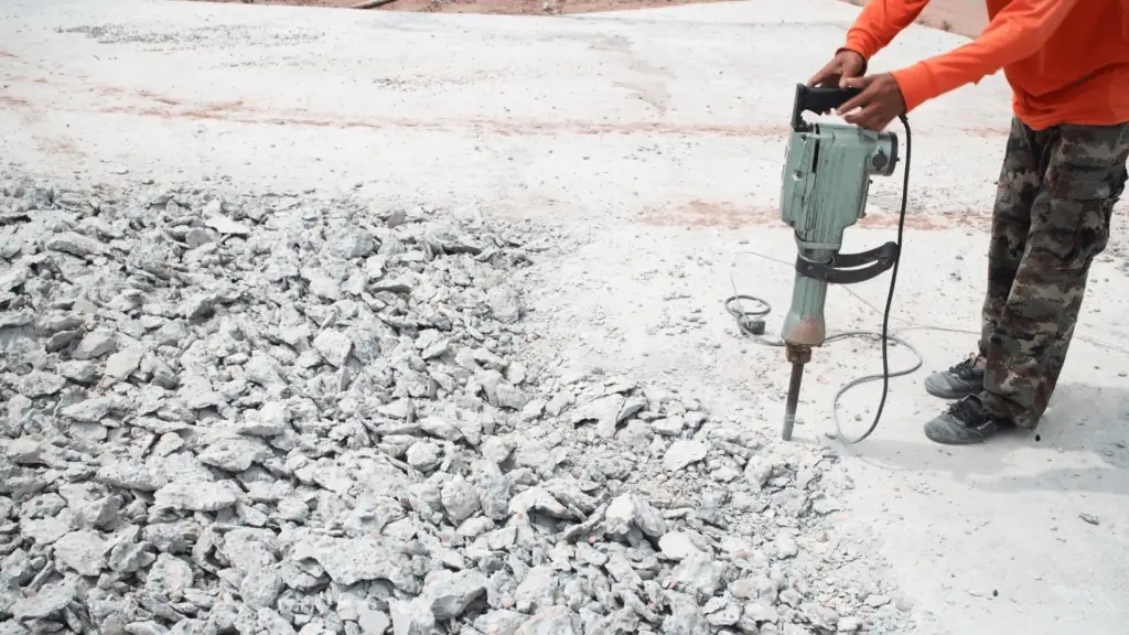 Concrete removal with jackhammer at a construction site, breaking up old concrete.